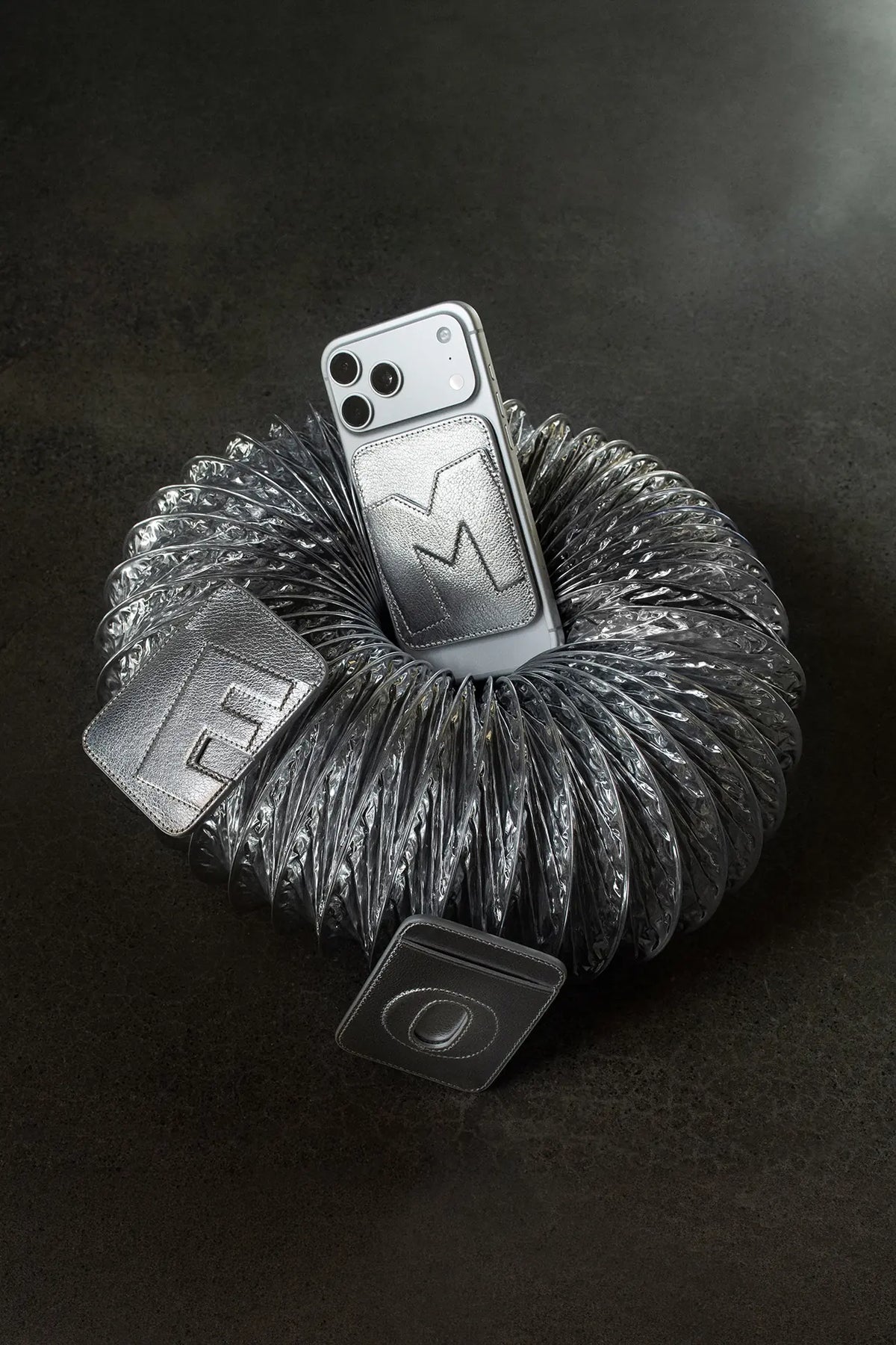 Initial MagSafe cardholders in Metallic Silver leather with the letters M, E and O, around a phone